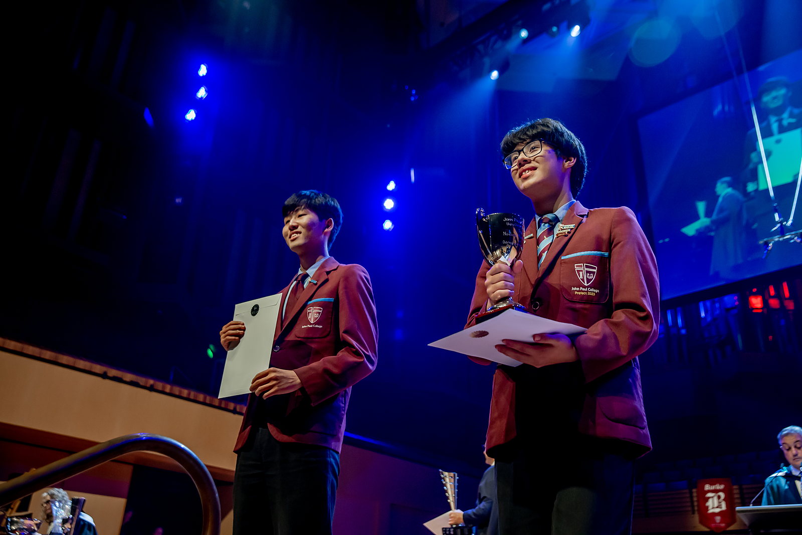 Adam Li on stage at John Paul College Speech Night, holding his award