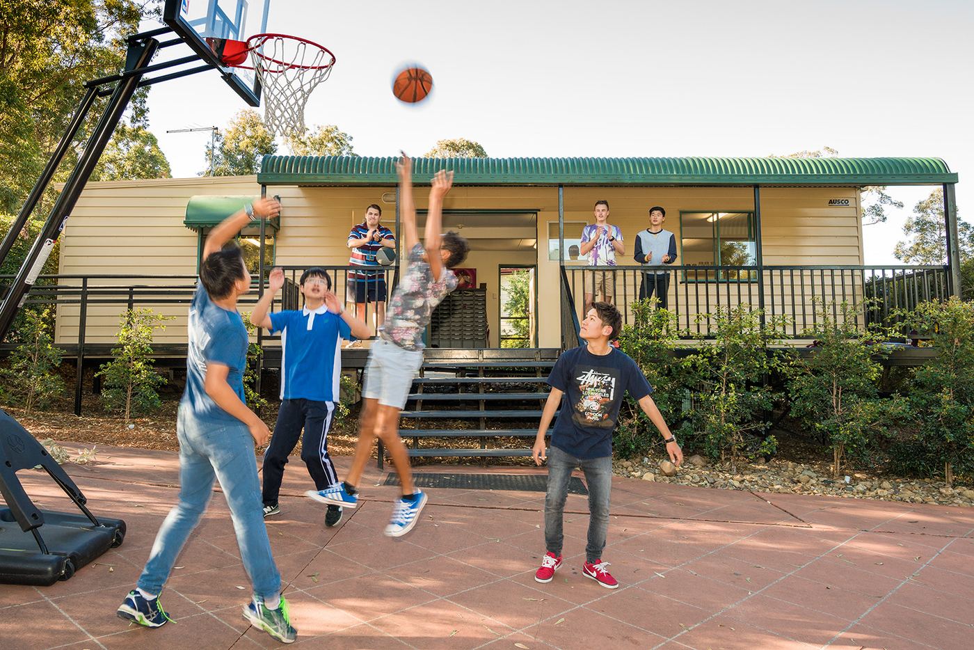 Boarding students playing basketball together on campus at John Paul College