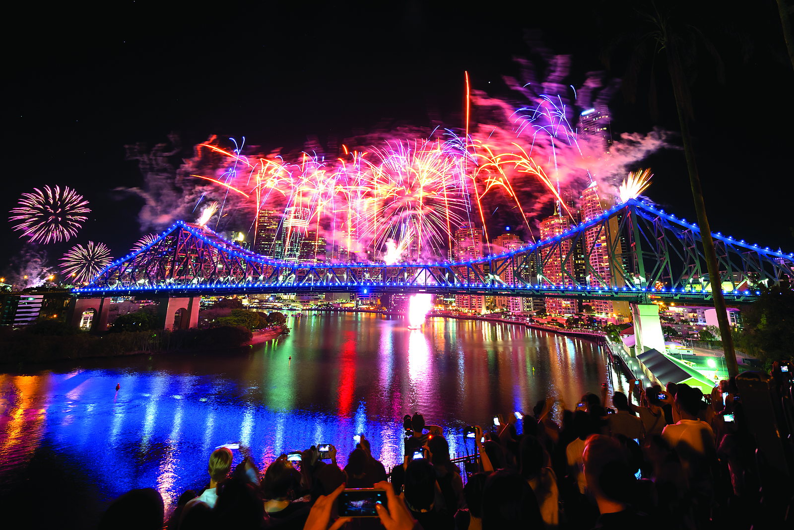 Crowds watching fireworks over the Story Bridge and the Brisbane River at a city celebration