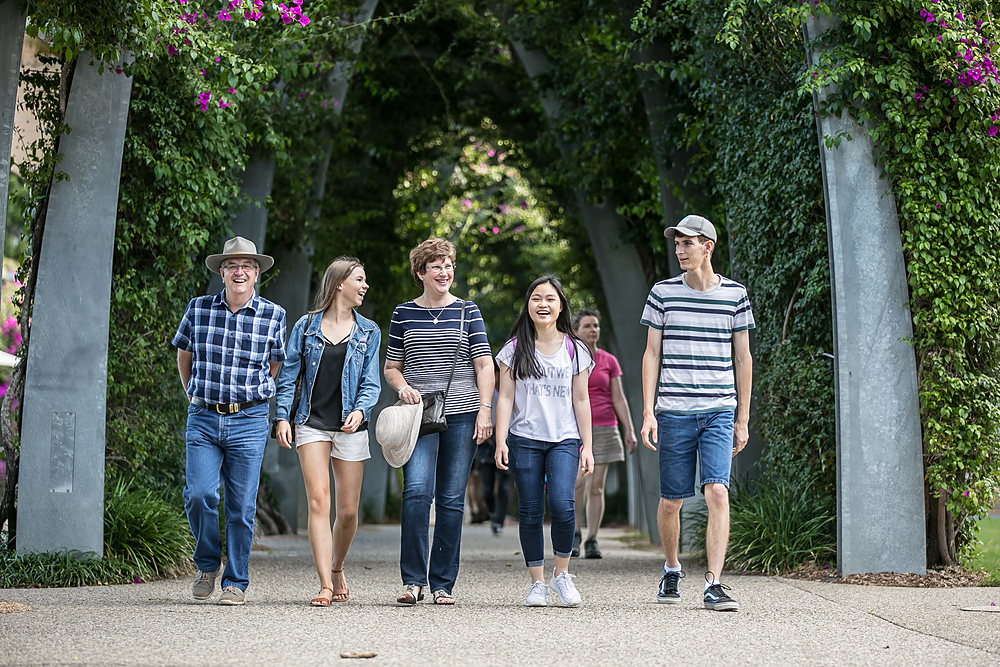 An international student walking through the South Bank parklands with their homestay family on a sunny afternoon