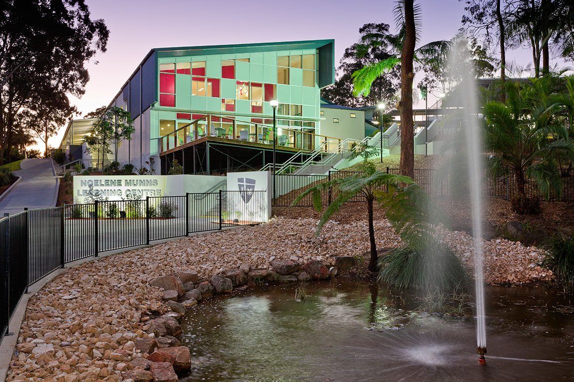 The Noelene Munns Learning Centre building with its coloured facade and water feature at dusk