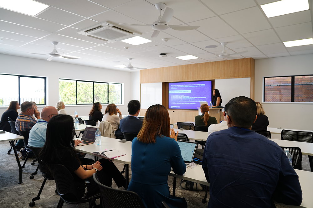Delegates in a classroom listen to a Student Support Services stream session on working with study travel agents, presented by StudyTravel