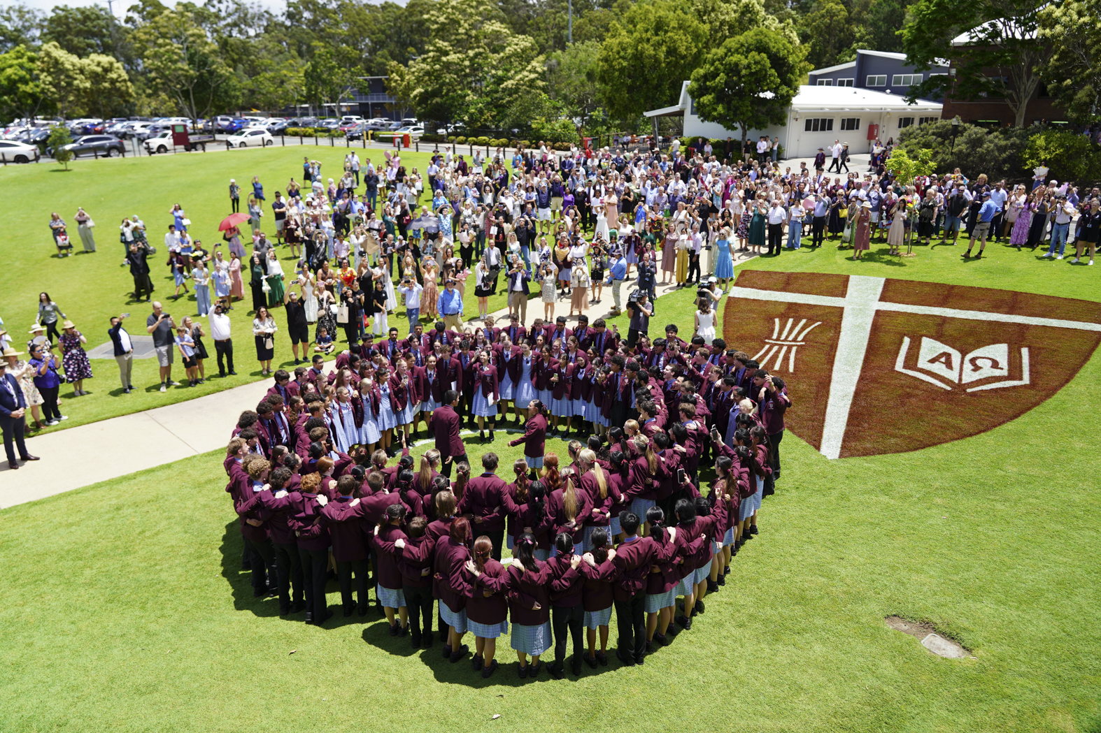John Paul College Year 12 students gathered around the College crest on the oval