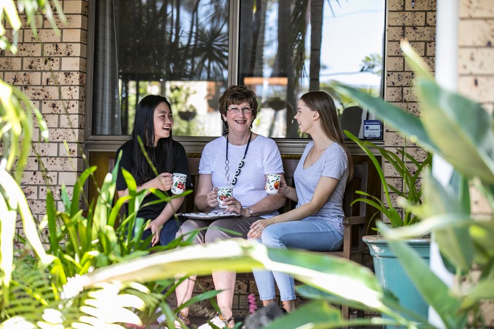 An international student laughing over afternoon tea with her JPC homestay family