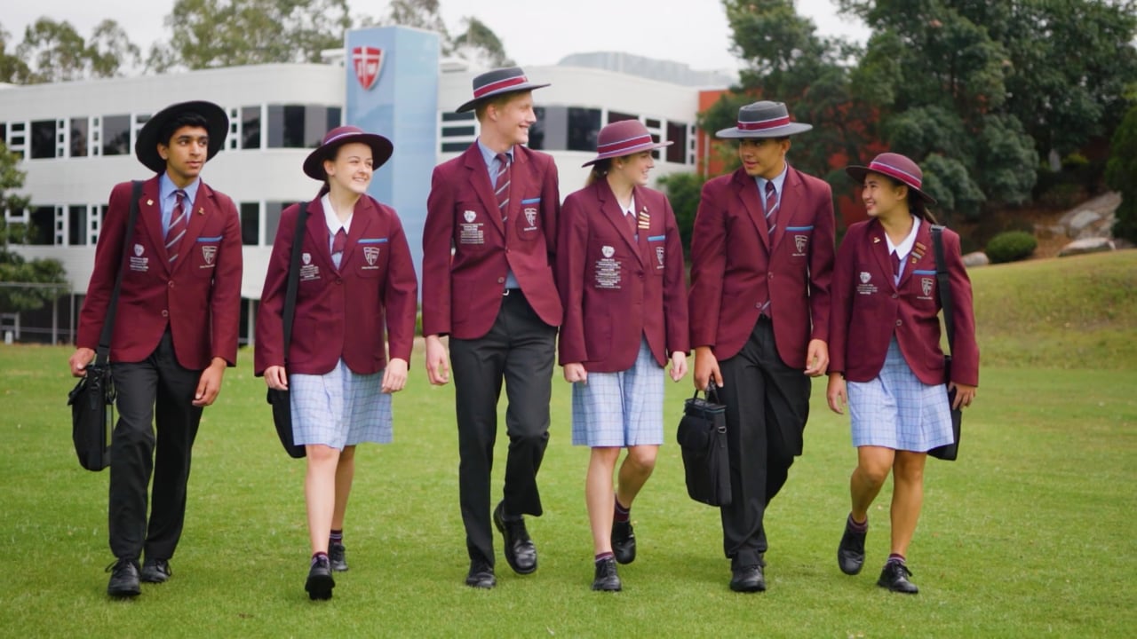 John Paul College students walking together across the campus lawn in College uniform