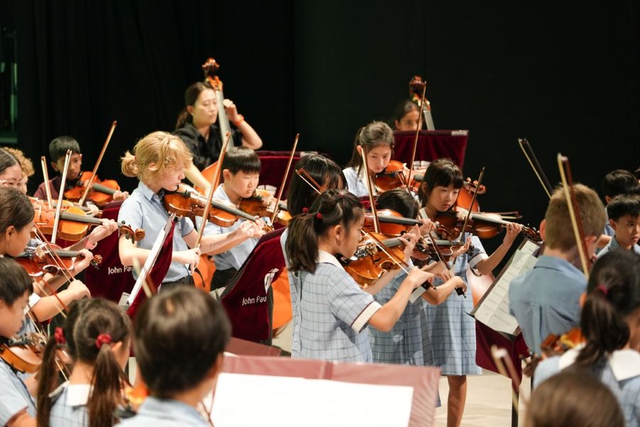A primary string orchestra of young violinists performing together on stage