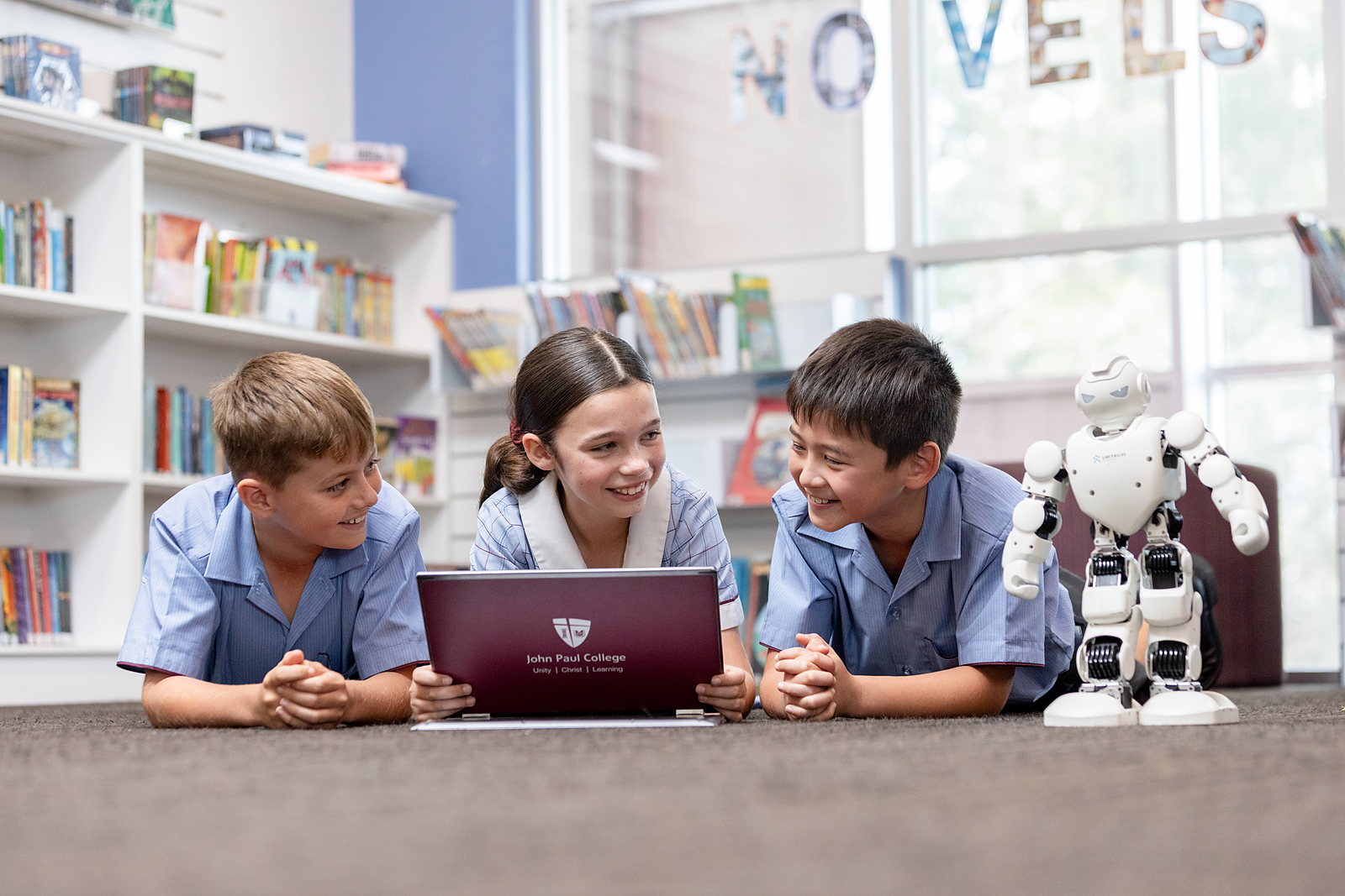 Primary students exploring a robot together in the JPC library