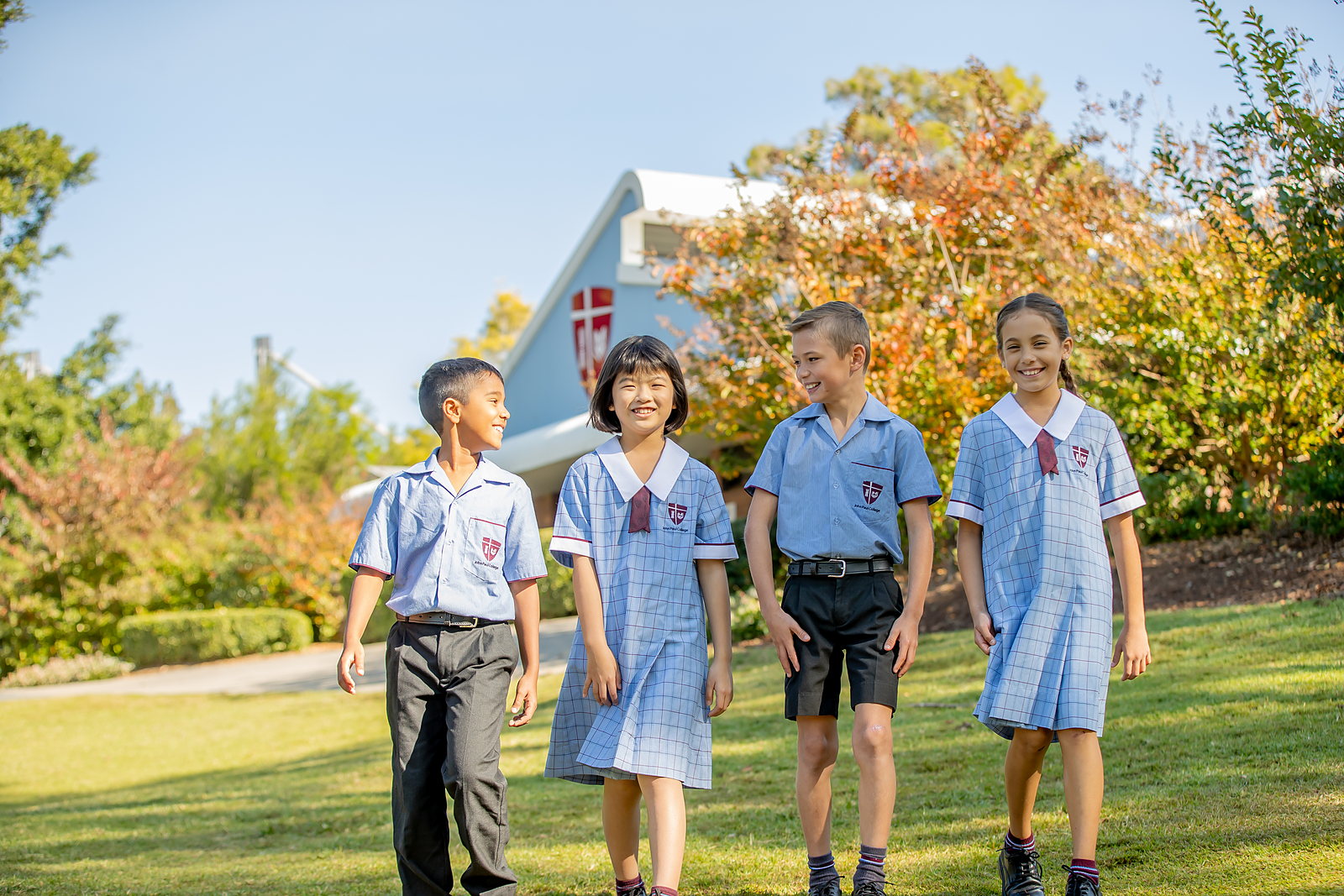 Happy John Paul College primary students walking together outdoors on a sunny day
