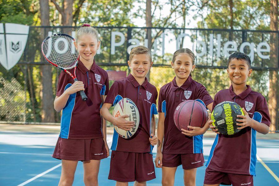 Primary students on the court holding rugby, basketball and tennis gear