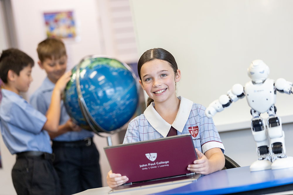 A girl beaming beside a humanoid robot and a globe as classmates explore behind