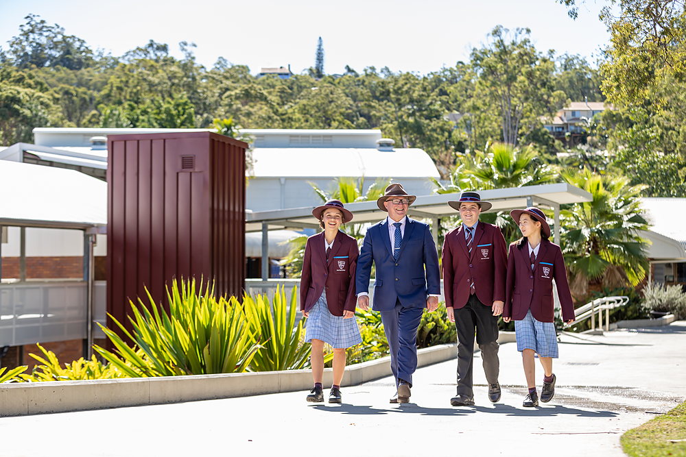 Two JPC secondary students in blazers on campus, one holding a basketball