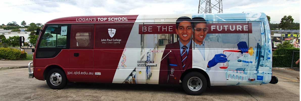 A John Paul College bus in College colours, signed for route 63, parked at the depot