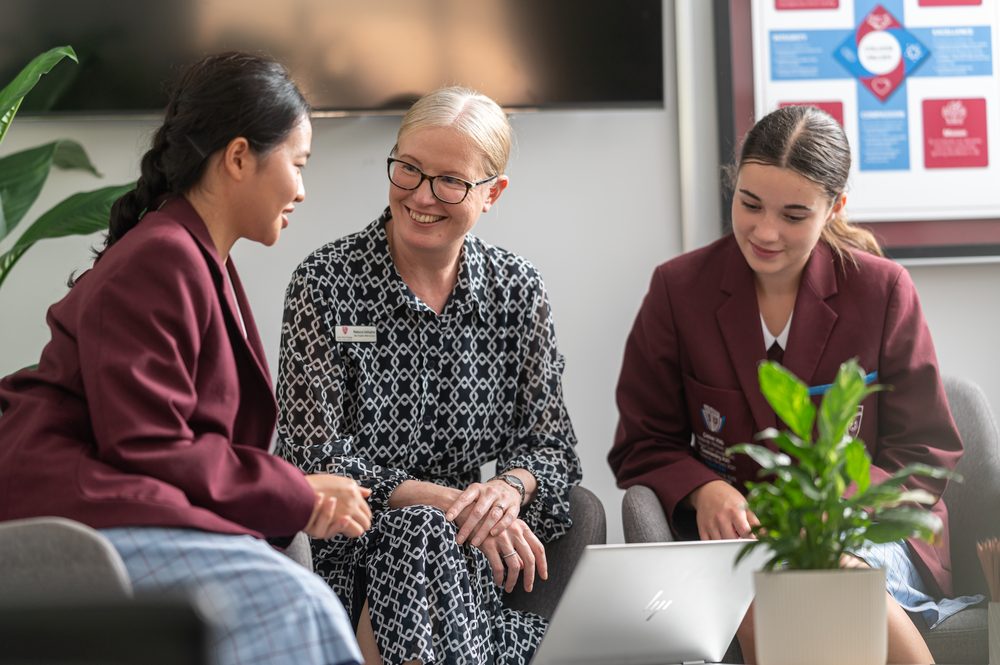 A John Paul College staff member talking with two international students in a pastoral care session