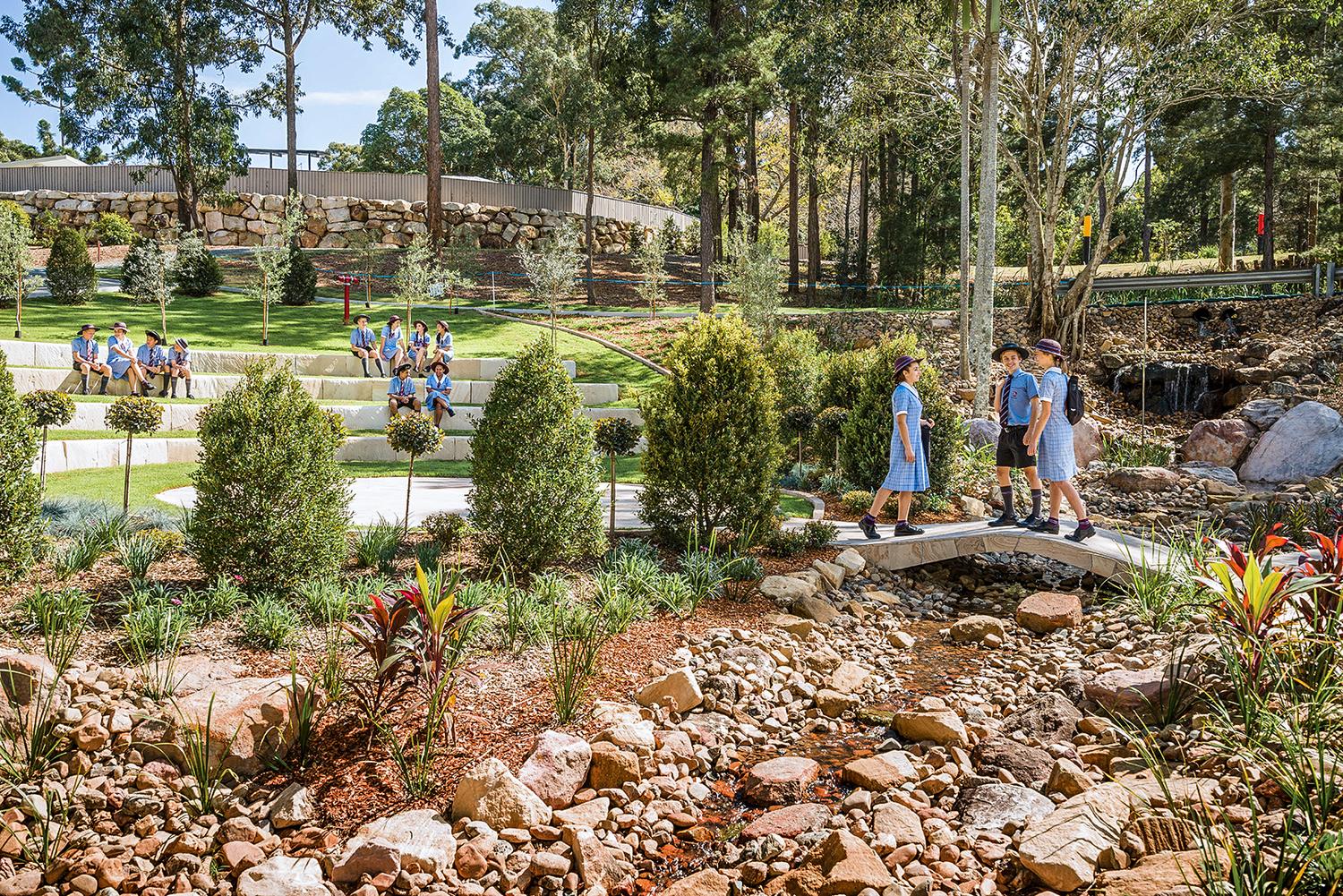 Students walking through the green, landscaped John Paul College campus grounds